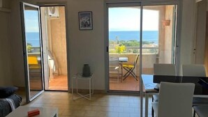 Quarto com varanda, mesa, cadeira e sofá.