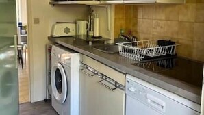 Uma cozinha compacta com máquina de lavar, micro-ondas e pia.