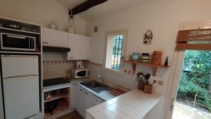 A compact kitchen with a microwave, toaster, sink, and a window overlooking greenery. - Petit Mas: ideal for families, garden, swimming pool, sea 15' away (Cavalaire-sur-Mer)