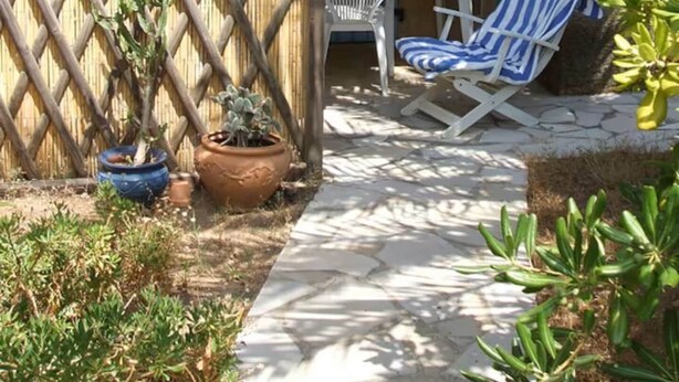 A patio with a blue umbrella, a white chair, and a small table. - Petit Mas: ideal for families, garden, swimming pool, sea 15' away (Cavalaire-sur-Mer)