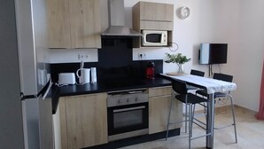 Una cucina compatta con frigorifero, microonde, forno e un tavolo con sedie.