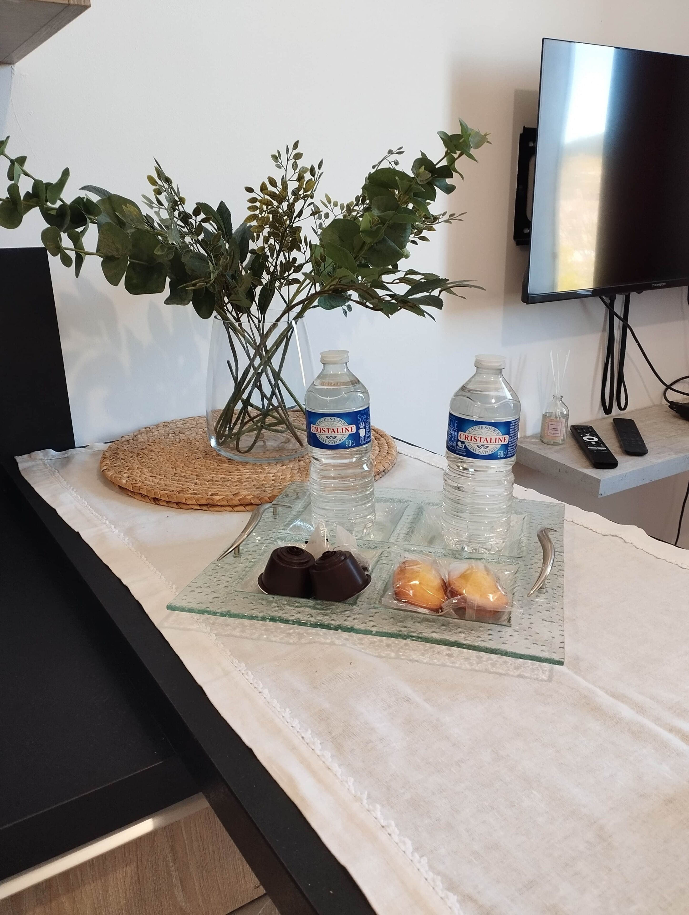 A glass table with water bottles, a plant, and snacks.
