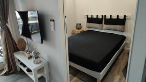 Une chambre à coucher moderne avec un lit, une table de chevet, une lampe et un téléviseur fixé au mur.