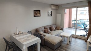 Un salon moderne comprenant un coin repas, un ensemble de canapés et un balcon avec vue.