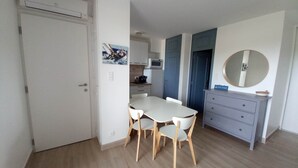 Una cocina compacta con comedor, una puerta blanca y un mueble pequeño con espejo.