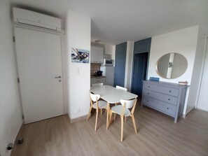 A compact kitchen with a dining area, a white door, and a small cabinet with a mirror. - Waterfront studio: sea view, air conditioning, wifi (Cogolin)