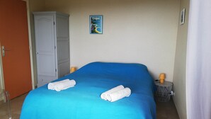 Et hotelværelse med en seng, et klædeskab, et lille bord med en lampe og et billede på væggen.