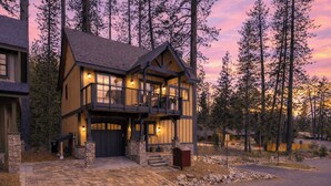 A two-story log cabin with a balcony, stone foundation, and a driveway leading to a garage. - Tahoe Glen by Avantstay Steps to Lake + Near Cave Rock + Heavenly Ski Resort Tahoe Rim Trail (Glenbrook)