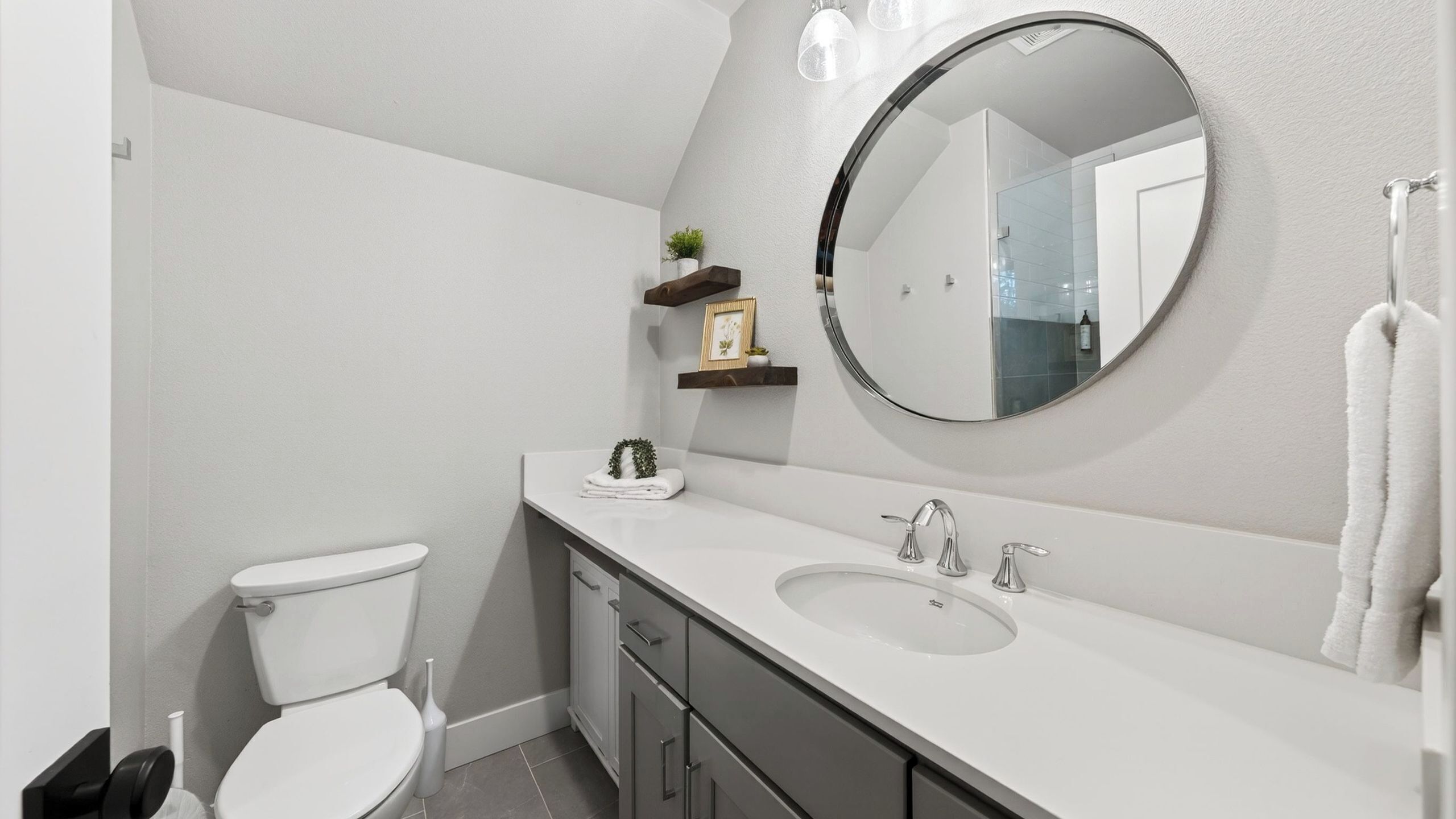 A modern bathroom with a toilet, a sink, a mirror, and a towel rack.