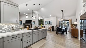 A modern kitchen with a large island, a dining area with a table and chairs, and a living space with a sofa and a TV. - Tahoe Glen by Avantstay Steps to Lake + Near Cave Rock + Heavenly Ski Resort Tahoe Rim Trail (Glenbrook)