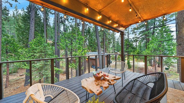 A wooden deck with a table and chairs, surrounded by trees. - Tahoe Glen by Avantstay Steps to Lake + Near Cave Rock + Heavenly Ski Resort Tahoe Rim Trail (Glenbrook)