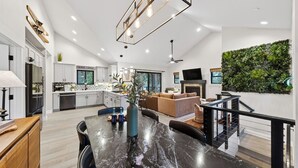 A modern kitchen with white cabinets, a dining area with a marble table, and a living room with a sofa and fireplace. - Tahoe Glen by Avantstay Steps to Lake + Near Cave Rock + Heavenly Ski Resort Tahoe Rim Trail (Glenbrook)