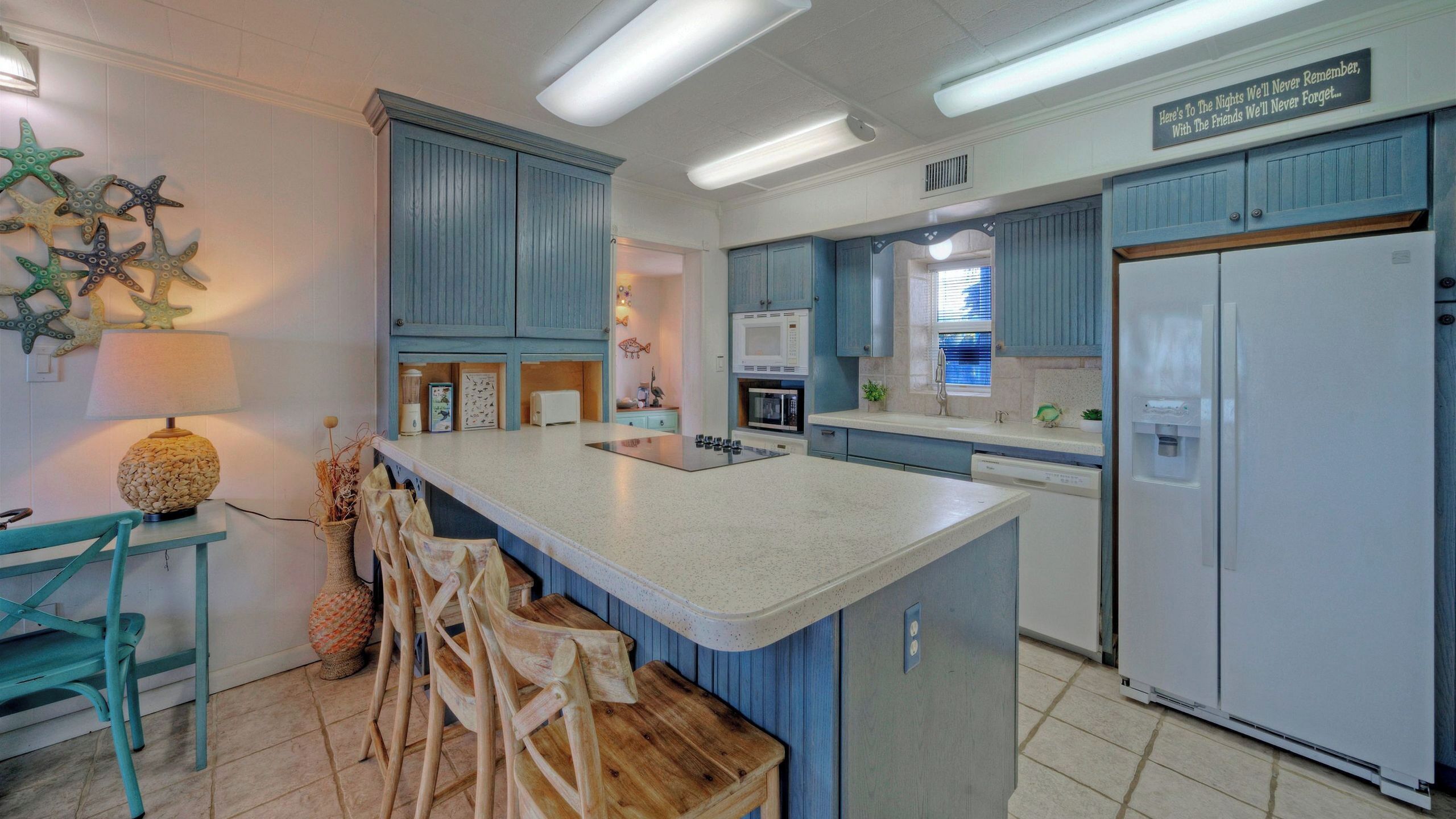 A kitchen with blue cabinets, a white refrigerator, and a central island with bar stools.
