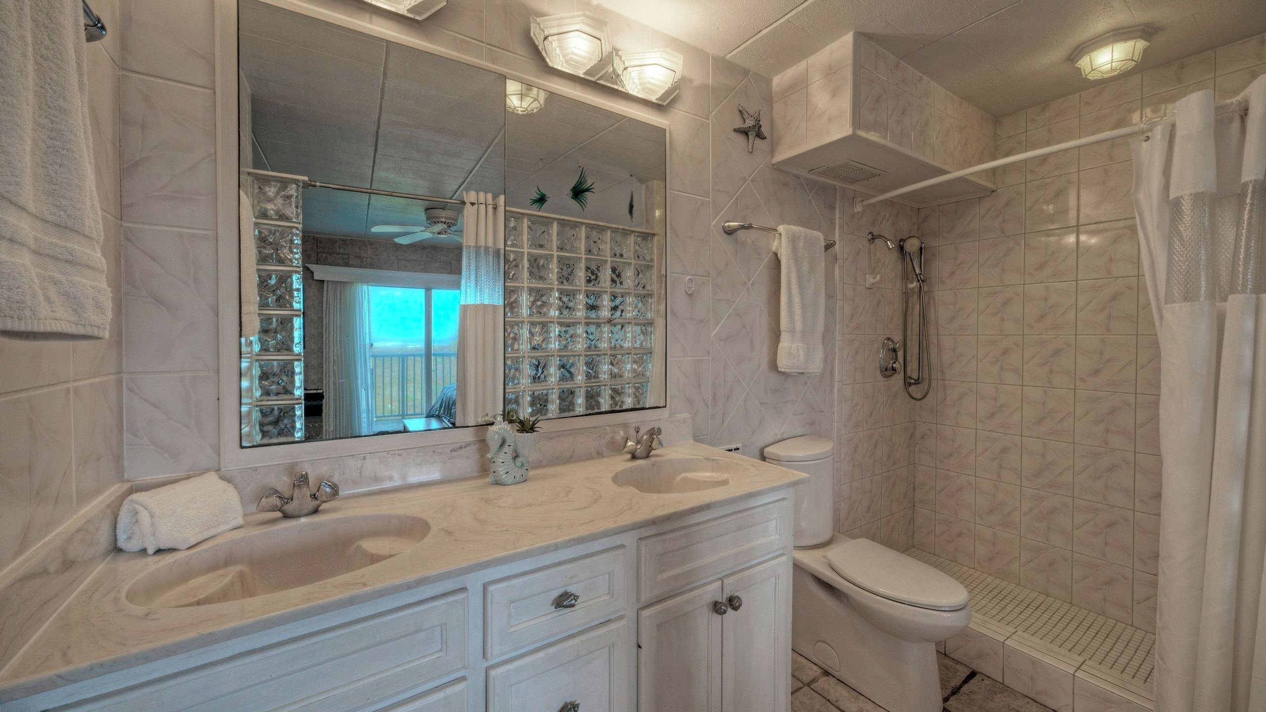 Une salle de bain avec deux lavabos, des toilettes, une douche et un grand miroir.