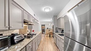 A modern kitchen with stainless steel appliances, a built-in oven, and a granite countertop. - Dallas Pool House - Hot Tub & Game Room - Near DFW, Stadium (Irving)