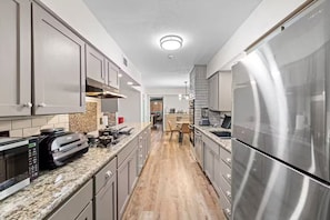 Eine moderne Küche mit Edelstahlgeräten, einem eingebauten Backofen und einer Arbeitsplatte aus Granit.
