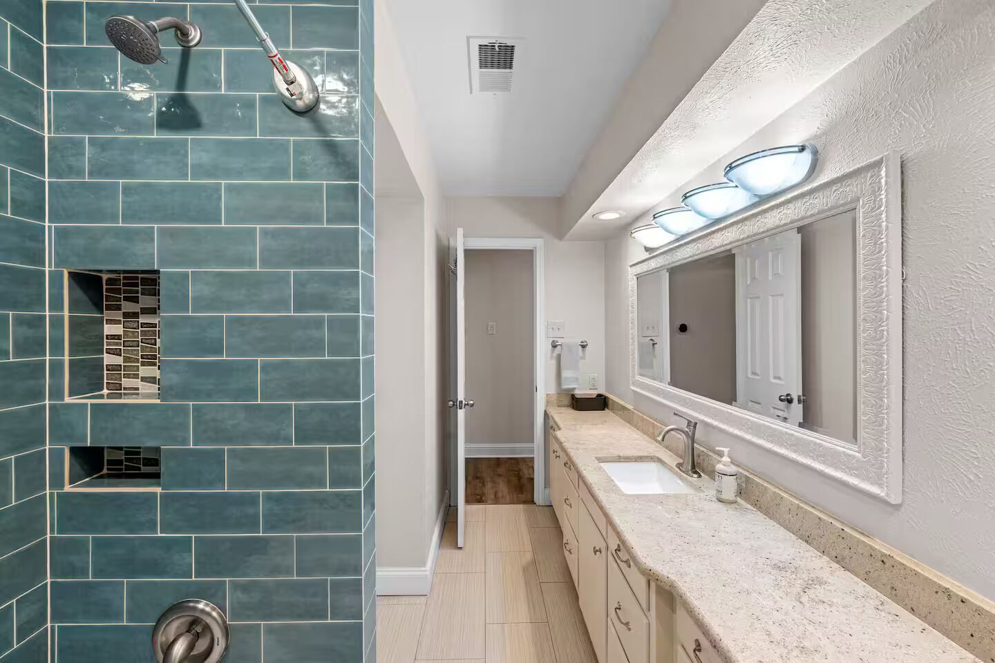 Une salle de bain avec une douche, un grand miroir et un meuble-lavabo avec deux vasques.