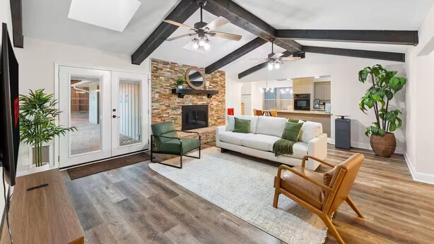 A spacious living area with a fireplace, wooden beams, and a large window. - Dallas Pool House - Hot Tub & Game Room - Near DFW, Stadium (Irving)