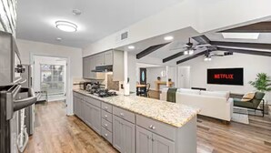 A modern kitchen with granite countertops, a built-in stove, and a large island. - Dallas Pool House - Hot Tub & Game Room - Near DFW, Stadium (Irving)