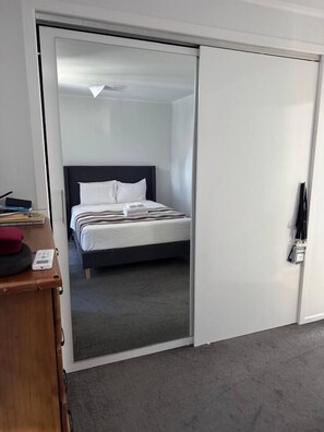 A hotel room with a bed, a desk with a telephone, and a wardrobe. - 2 bedroom Holiday home (Saint Heliers)