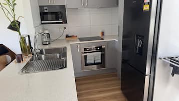 A kitchen with a stainless steel refrigerator, a microwave, and an oven built into the cabinetry.