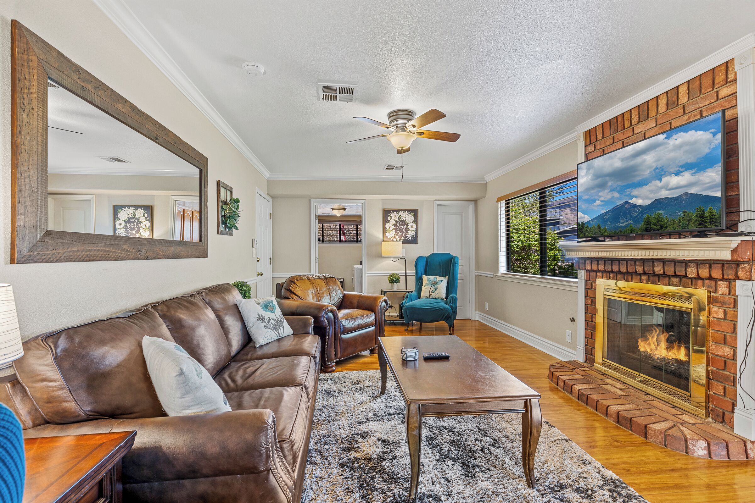 A living room with a fireplace, leather sofa, and a ceiling fan.