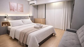 Un dormitorio moderno con cama, mesitas de noche, lámpara de noche, armario y sofá.