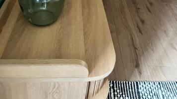Uma mesa de madeira com uma garrafa de vidro e um objeto amarelo em cima.