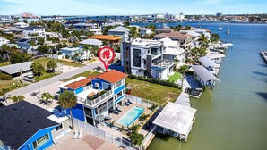 Zona residencial costera con una casa de dos plantas que cuenta con un balcón, piscina y un muelle que se adentra en el agua.