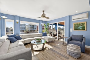 A modern living room with a sectional sofa, a glass coffee table, and a blue armchair. - Blue Bay View - Canal Front- Heated Pool (Fort Myers Beach)