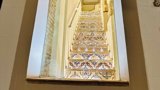 Un escalier orné de motifs complexes en carreaux de céramique menant à un tableau encadré.