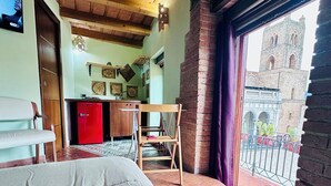 Une chambre à coucher avec un lit, un plafond en bois, une fenêtre donnant sur un immeuble et un réfrigérateur rouge.