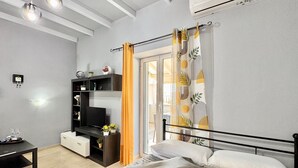 Ein modernes Schlafzimmer mit einem Bett, einem Fernseher, einer Ablage mit Dekoration und einem Fenster mit Vorhängen.