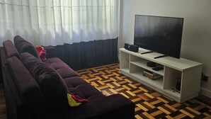 Una sala de estar con un sofá, un televisor sobre un mueble bajo y un piso con diseño.
