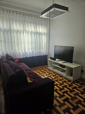 Ein Wohnzimmer mit einer Couch, einem Fernseher auf einem Schrank und einem gestreiften Boden.