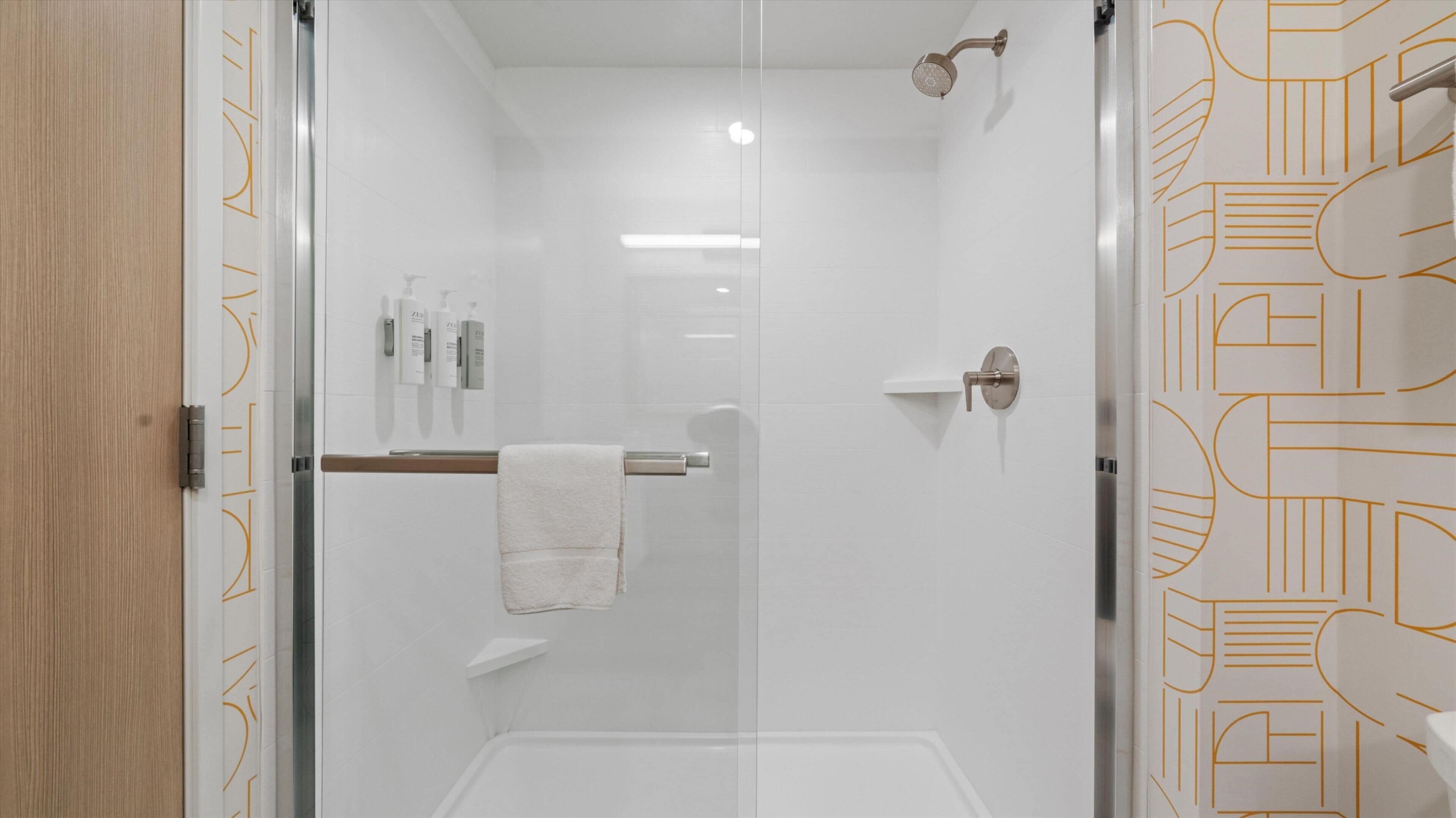 Un bagno moderno con box doccia in vetro, un appendi-asciugamani e una porta con motivo geometrico.