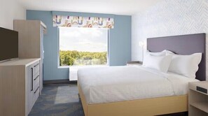 Ein Hotelzimmer mit Bett, Schreibtisch, Fernseher und Fenster mit Blick auf Grünflächen.