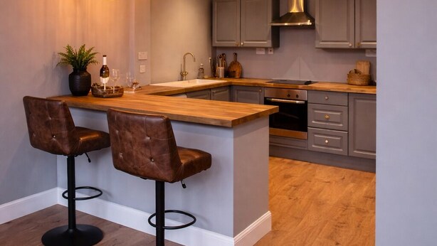 A modern kitchen with a central island, bar stools, pendant lighting, and wooden flooring. - Cozy Edinburgh Escape (Edinburgh)