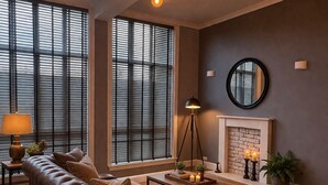 A living room with a brown leather sofa, a coffee table, a floor lamp, a fireplace, and large windows with blinds. - Cozy Edinburgh Escape (Edinburgh)