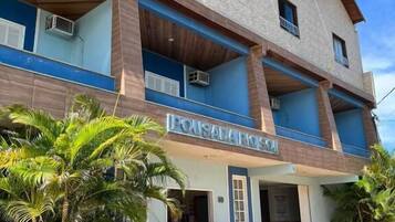 Um edifício de vários andares com uma placa que diz 'POUSADA RIO'.