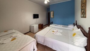 A hotel room with two beds, a ceiling fan, a television, and a small desk with a lamp. - Pousada Rio sol (Sao Joao Da Barra)