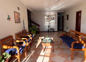 A spacious living area with wooden furniture, a tiled floor, and a staircase leading to an upper level.