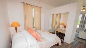 A bedroom with a bed, a mirror, and a window with curtains. - Ojai’s Sage Ranch Guest Villa (Ojai)