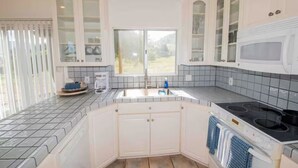 A modern kitchen with white cabinets, a built-in microwave, a double sink, and a large window. - Ojai’s Sage Ranch Guest Villa (Ojai)