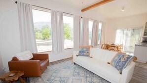 A living room with a brown leather sofa, a white sofa with patterned cushions, a wooden coffee table, and a patterned rug. - Ojai’s Sage Ranch Guest Villa (Ojai)