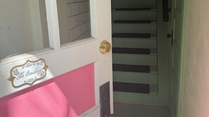 A door with a 'No Smoking' sign, a pink and white door frame, and a staircase leading to a landing.