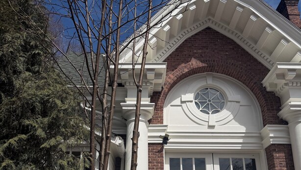 A building with a brick facade, white columns, and a large arched window.