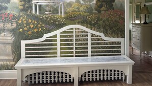 A room with a mural of a garden scene, a white bench, and a dresser with drawers.