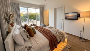 A bedroom with a bed, a TV, a ceiling fan, and a view of the outdoors. - Cozy 2BR Villa in Ocean Village (Sosúa)