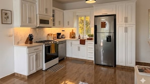 A modern kitchen with white cabinetry, stainless steel appliances, and a pendant light. - Cozy 2BR Villa in Ocean Village (Sosúa)